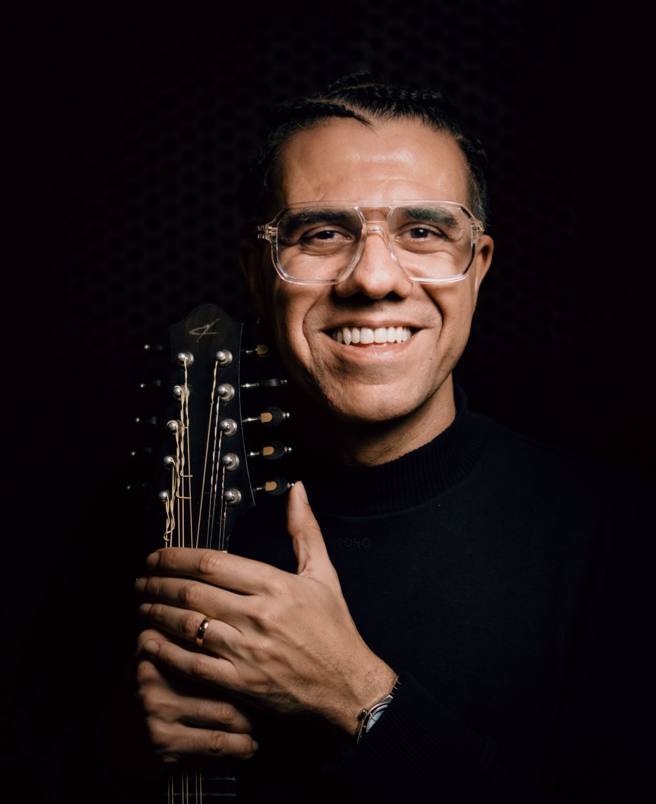 Hamilton de Holanda sorrindo, com o bandolim de 10 cordas, em fundo escuro