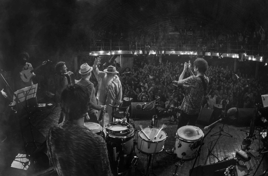 Do fundo do palco, Hermeto Pascoal, Hamilton de Holanda e a banda diante do Circo Voador lotado, em preto e branco